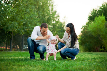 Happy family mother, father, child daughter. Happy young family spending time together outside in green nature. Happy family resting together on the green grass. Happy family having fun outdoors