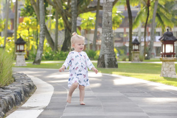 Adorable baby girl in the beautiful tropical park, candid outdoor portrait