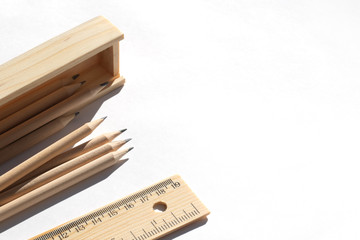 Pencil case and pencils are lying on the table in bright daylight. Natural unpainted wood. Eco-friendly materials