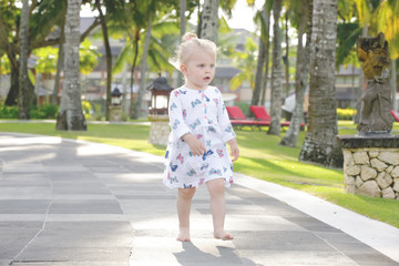 Adorable baby girl in the beautiful tropical park, candid outdoor portrait