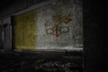 painted flag of vatican city on the dirty old wall in an abandoned ruined house.