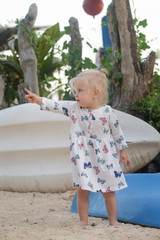 Cute little girl standing on the beach next to the kayak