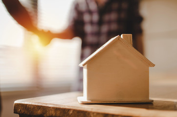 wooden house model on workplace desk with construction worker team hands shaking greeting start up plan new project contract in office center at construction site, partnership and contractor concept