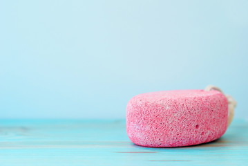 Natural pumice stone with white rope on wooden background.
