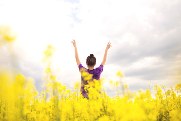Young happy woman in canola field. Yellow field flowers. Beautiful stylish romantic. Colza, rapeseed.