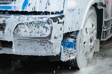 The element of the cab of the blue truck in the lather during washing. - 271368724