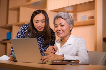 natural lifestyle portrait of two business partners or work colleagues women collaborating and coworking happy and cheerful at office laptop computer desk