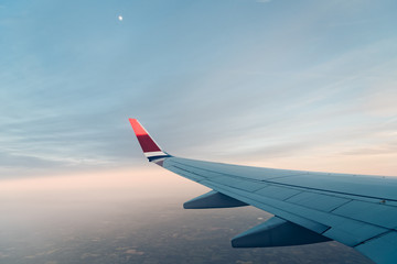 Fototapeta na wymiar Wing of airplane flying against sky at sunset