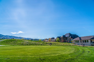 Obraz premium Residential houses on a terrain with vivid green grasses viewed on a sunny day