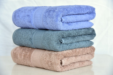 STACKED COLOR SOFT COTTON BATH TOWEL ISOLATED ON WHITE BACKGROUND.