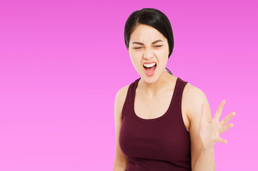 Angry Asian woman shouting to the front with mouth wide open on isolated purple background