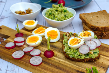 Fototapeta na wymiar Sandwiches with avocado guacamole fresh radish and boiled egg