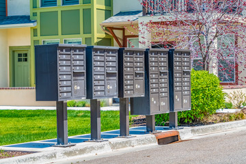 Row of cluster mailboxes with numbered compartments on a sunlit sidewalk