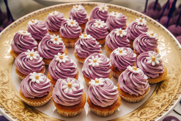 A lot of cupcakes on a festive plate. Background with sweets