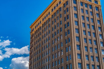 Exterior of a building with the cloudy blue sky reflected on the glass windows