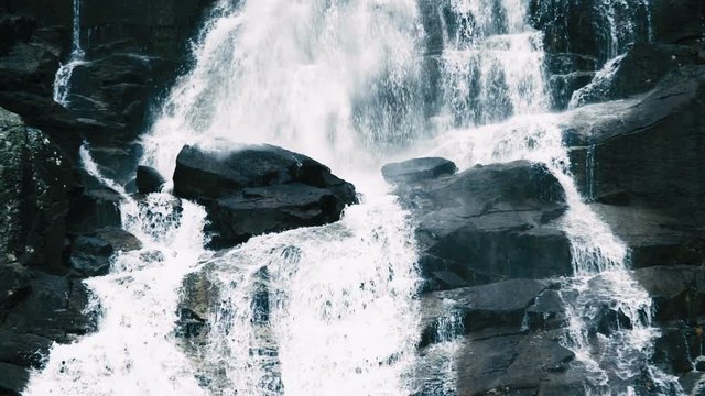 4K waterfall slow motion footage water falling backwards by black sharp rocks