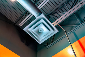 Close up view of a square air conditioner ventilator connected to a pipe