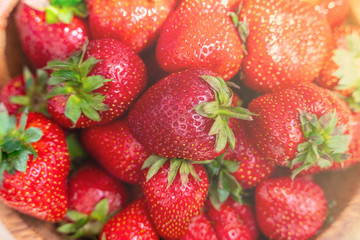 Fresh beautiful strawberries in wooden bowl top view. Strawberry fruits on wooden table copy space.