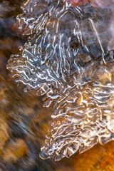 Close up of translucent frozen water on a rocky stream during winter