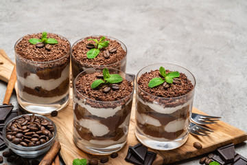 Classic tiramisu dessert in a glass on dark concrete background
