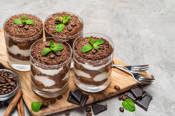 Classic tiramisu dessert in a glass on dark concrete background