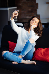 Portrait of a beautiful woman taking a selfie with her smart phone at home