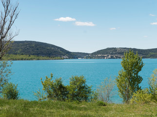 Fototapeta na wymiar Paysage d'eau bleue turquoise du lac de Sainte-Croix au pied des gorges du Verdon depuis le chemin forestier de Bauduen. Alpes-de-Haute-Provence