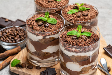 Classic tiramisu dessert in a glass on dark concrete background