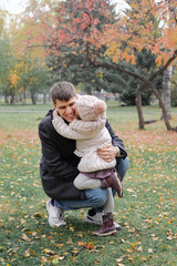 Fototapeta premium Child hugging and kissing their dad. Father smiles when his daughter ran up to him on the background of autumn park.