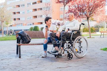Beautiful picture of a boy hanging out with his grandfather sitting on a wheelchair