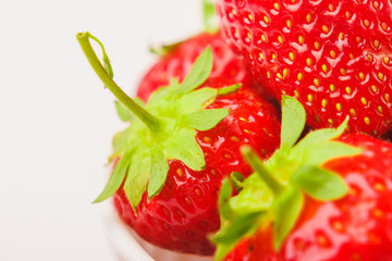 Red ripe strawberry in the white bowl, light background