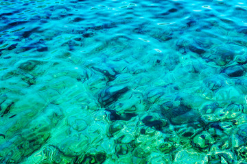 Transparent turquoise sea with sun glare. Background close-up. Space for text.