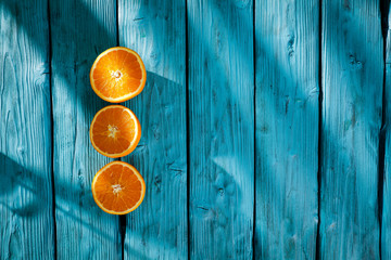 Fresh orange fruits for juice on blue wooden board with shadow. Free space for your decoration and summer time. Healthy nutrition. 