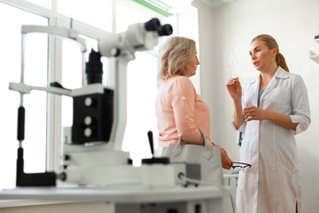 Diligent long-haired ophthalmologist actively gesturing while talking