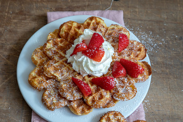Waffeln, Erdbeeren und Sahne auf einem weißen Teller