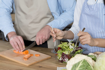 Mid-section of couple preparing food in kitchen counter