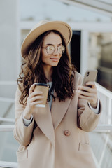 You have new message. Beautiful young woman in sunglasses using her smart phone with smile while...