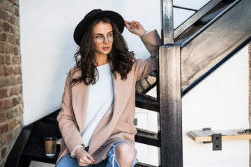 Portrait of woman wearing a coat. Beautiful young woman in coat descending steps in modern...