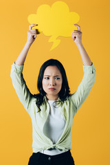 sad asian woman holding cloud speech bubble, isolated on yellow