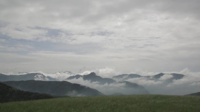 Wide shot of mountain peaks and clouds sitting in them, Monte Colma, Italy