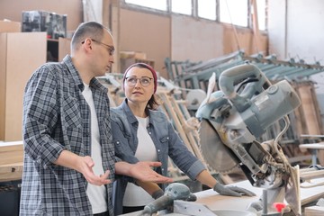Industrial portrait of two working men and woman, talking at machine tools