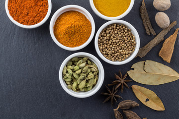 Spices in little white bowls on black slate background - Indian spice top view photo