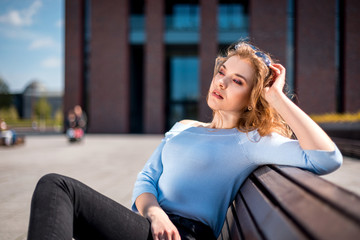 Young woman sitting on bench in city urban space during summer