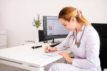 Young blonde doctor working on computer in new clinic. Helthcare concept