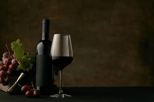 Front view of tasty fruit plate of grapes with the wine bottle and glass on dark studio background, copy space to insert your text or image. Gourmet food and drink.