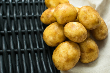  potatoes against a black basket and napkin.