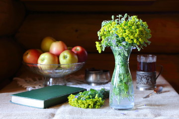 Bouquet of wild flowers in a glass vase on the table by the window.