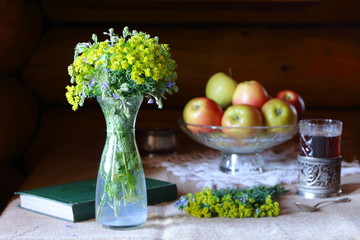 Bouquet of wild flowers in a glass vase on the table by the window.