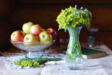 Bouquet of wild flowers in a glass vase on the table by the window.
