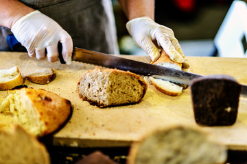 Woman cutting bread on wooden board. Bakehouse. Bread production.